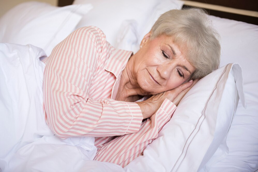Older adult sleeping peacefully in bed with soft lighting, reflecting the natural changes in sleep that come with age.