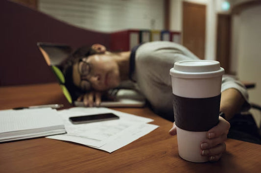 Tired person at work with a cup of coffee, showing mental fatigue after a bad night's sleep.