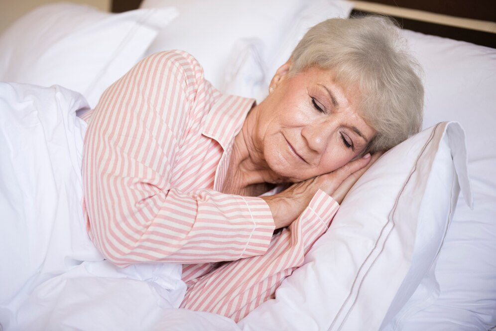 Older adult sleeping peacefully in bed with soft lighting, reflecting the natural changes in sleep that come with age.
