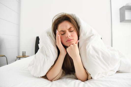 Exhausted person lying under the covers with eyes open, struggling to fall asleep, representing frustration of light sleepers.